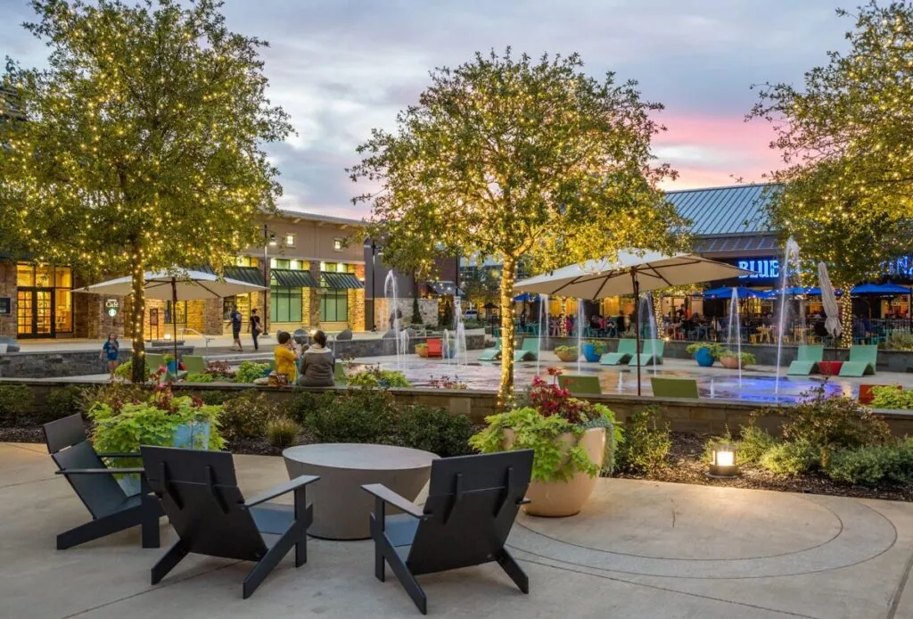 Fountains, lounge chairs and string-lit trees at The Shops at Highland Village at dusk