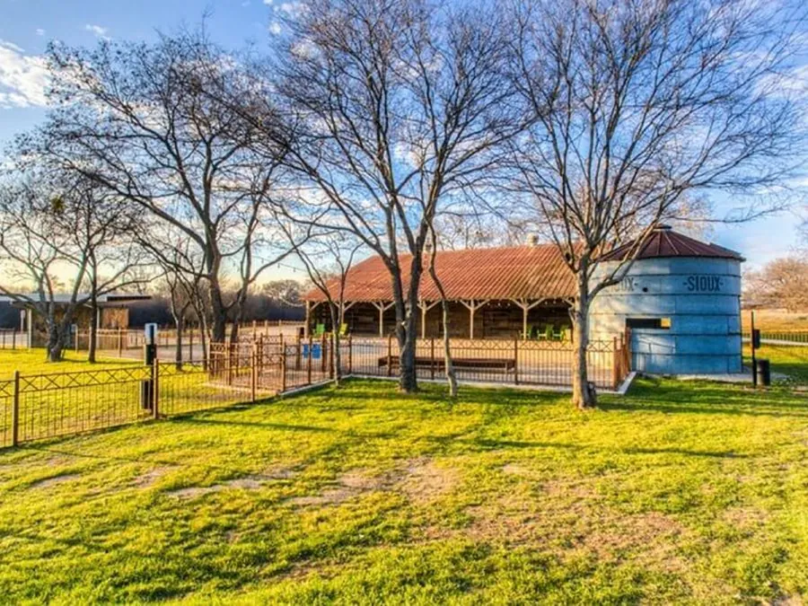 Covered patio pavilion and blue silo beside a fenced lawn in Argyle, TX