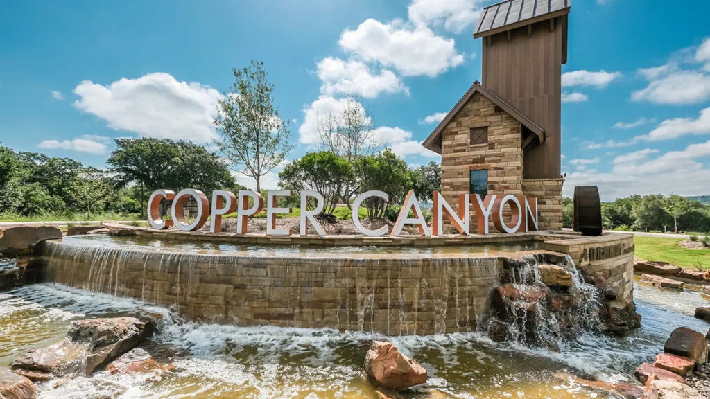 Copper Canyon town sign above a stone waterfall fountain