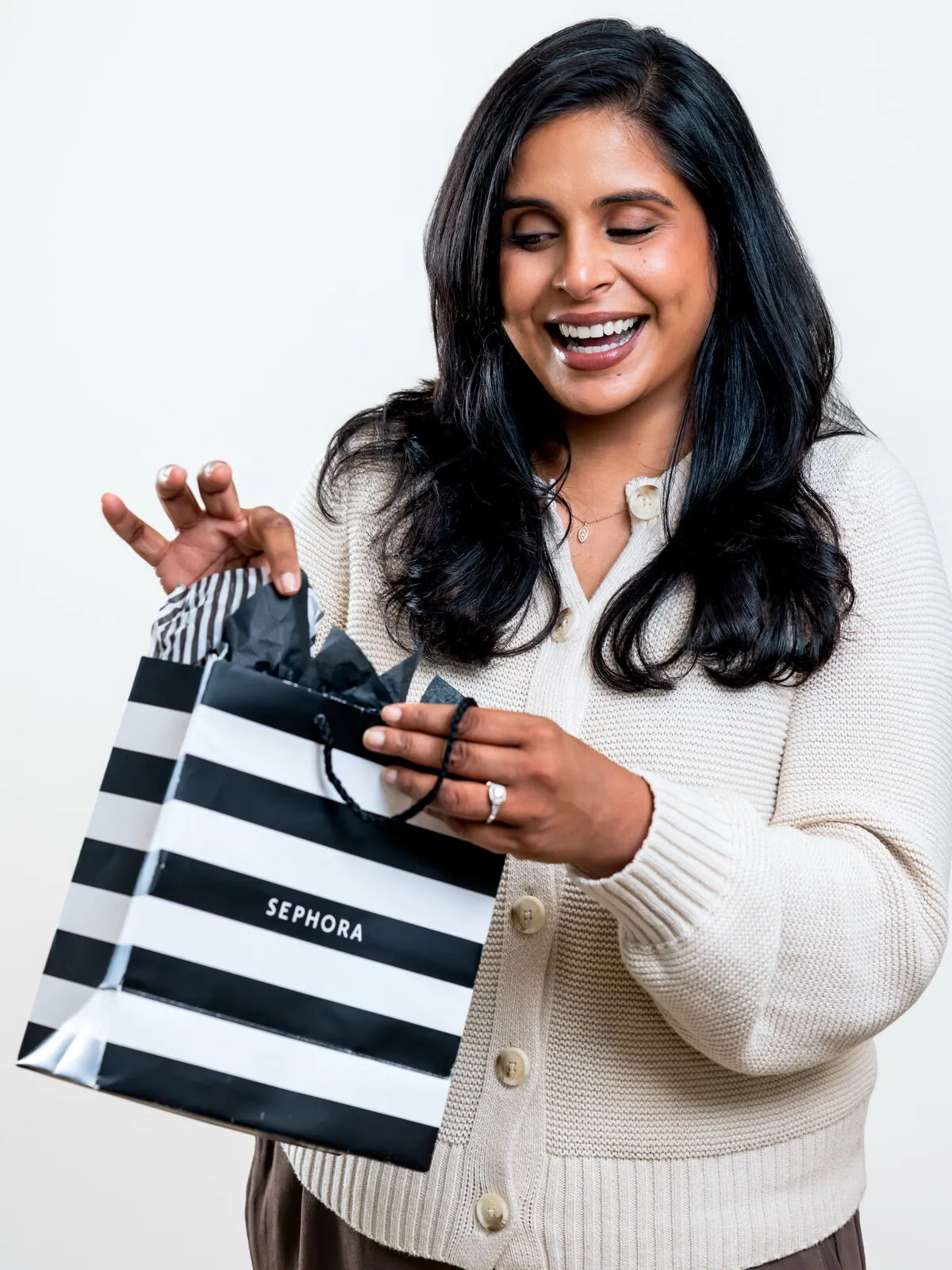 Dr. Ashley Chennankara laughing as she opens a Sephora shopping bag