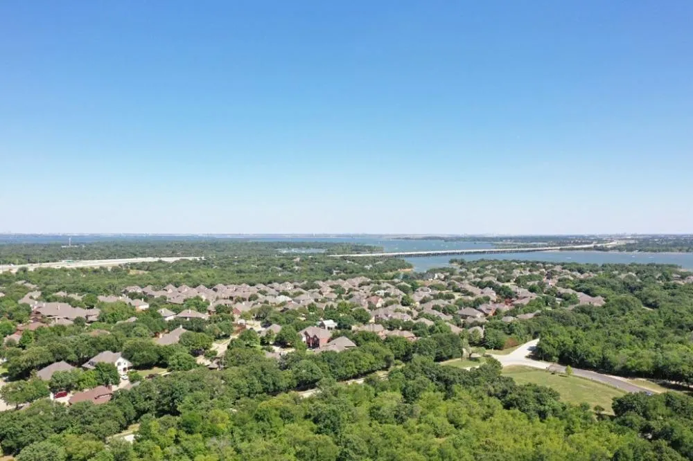 Aerial view of wooded neighborhoods and a lake bridge in Hickory Creek, TX
