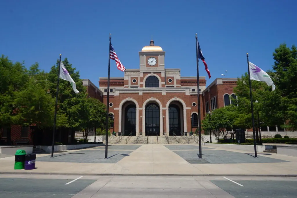 Red-brick civic building with a clock tower and flags in Lewisville, TX