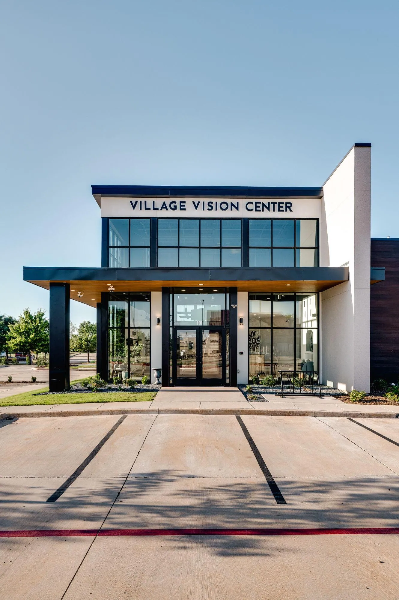 Modern two-story eye care office with tall black-framed windows and the clinic's sign above the front entrance