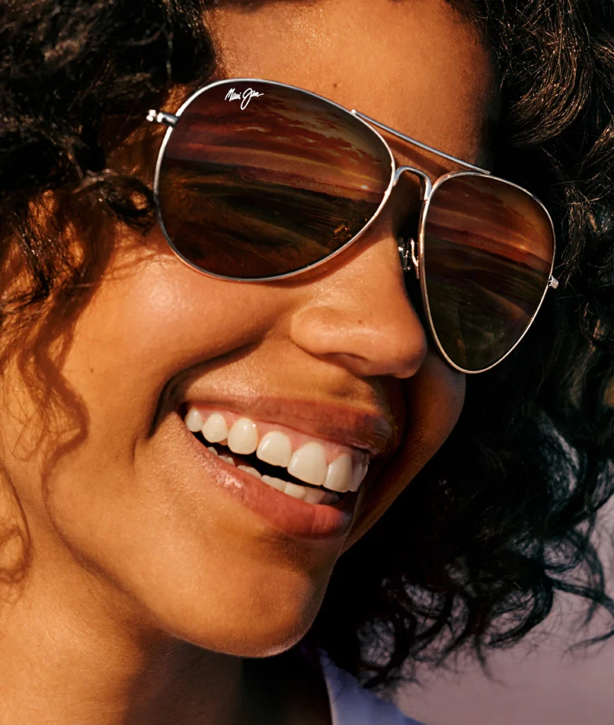 Smiling woman wearing Maui Jim aviator sunglasses with brown lenses