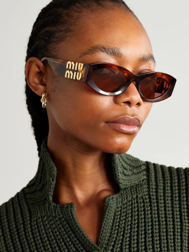Woman wearing Miu Miu tortoiseshell sunglasses with the gold logo on the temple