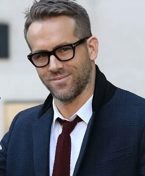 Man in a navy jacket wearing thick black Tom Ford eyeglasses