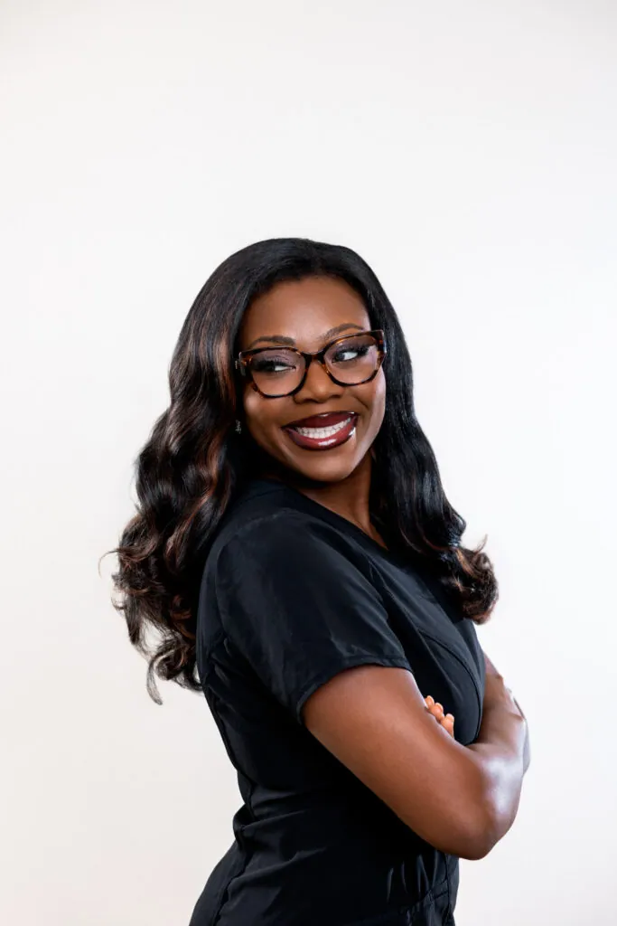 Smiling woman with arms crossed wearing black cat-eye eyeglasses