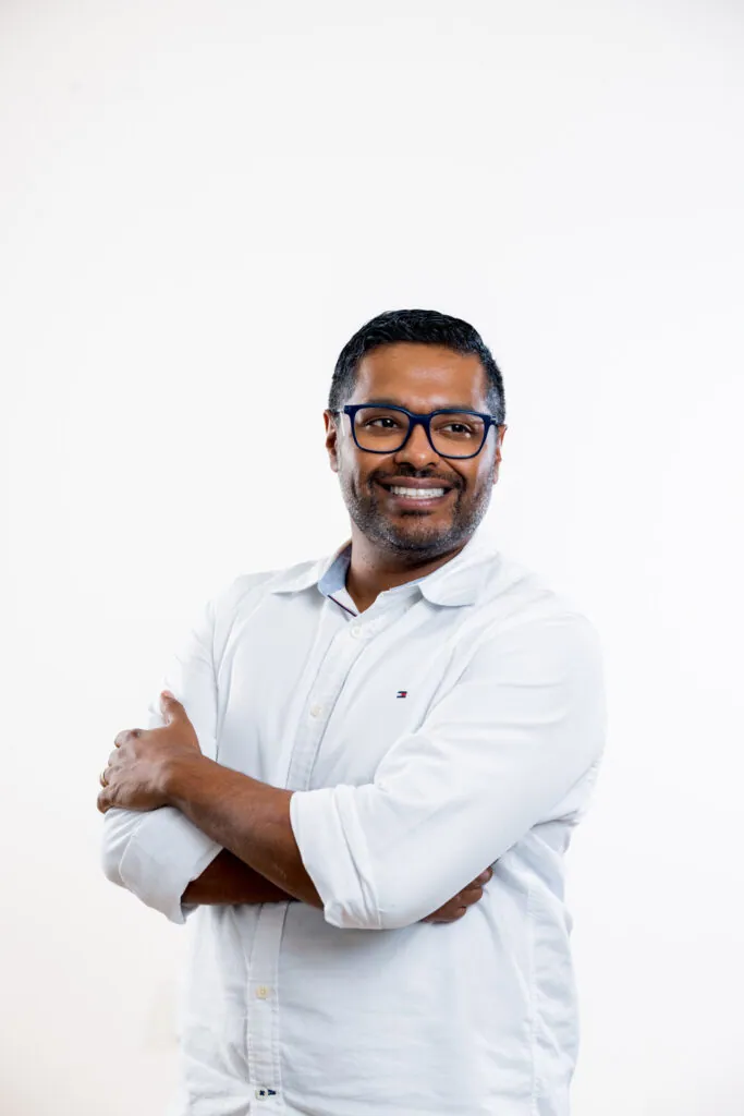 Smiling man in a white shirt wearing black rectangular eyeglasses