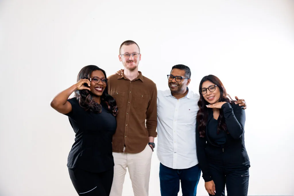 Four friends in eyeglasses laughing and posing together