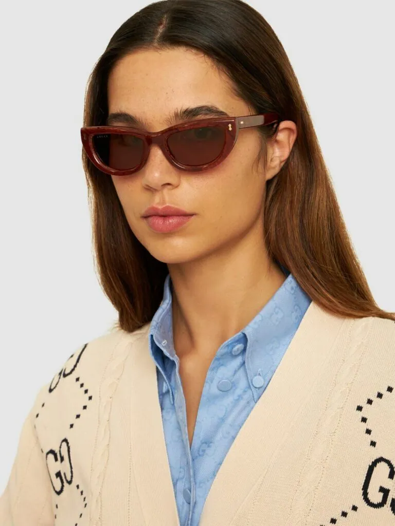 Woman wearing Gucci red cat-eye sunglasses and a GG cardigan