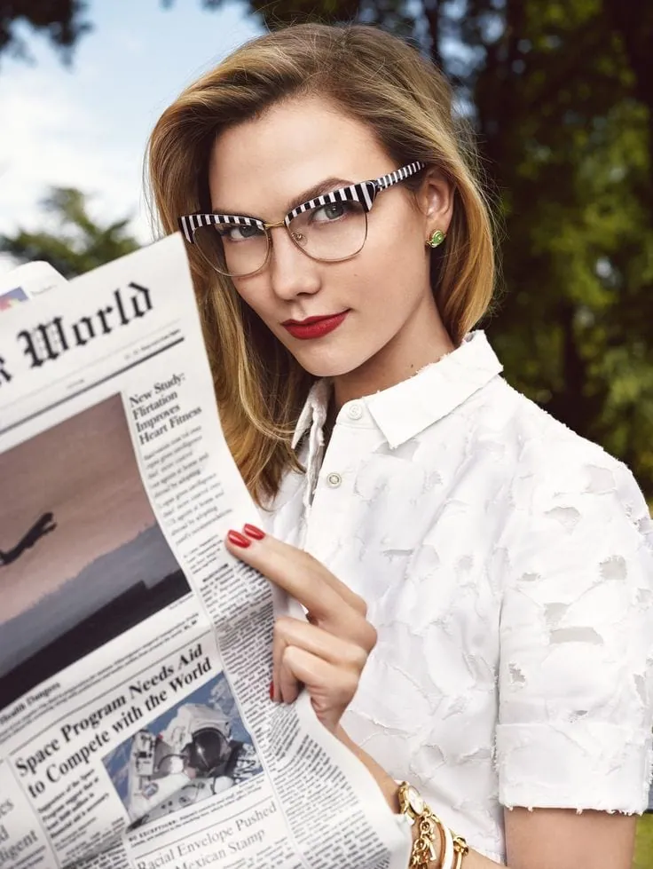 Woman wearing Kate Spade black-and-white striped eyeglasses while holding a newspaper