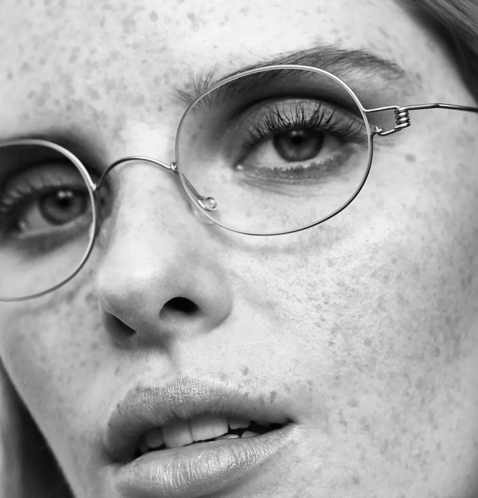 Black-and-white close-up of a woman wearing thin rimless Lindberg titanium eyeglasses