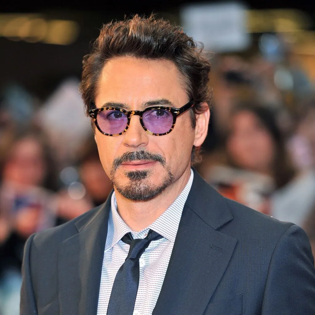 Man in a suit wearing Moscot round tortoiseshell frames with purple tinted lenses