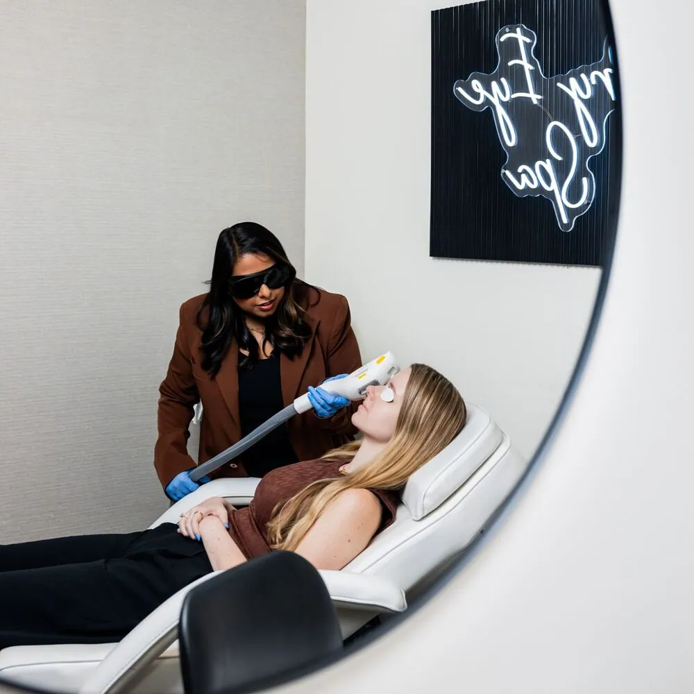Reflected in a round mirror, a Village Vision Center doctor treats a patient’s eyes with OptiLight in the Dry Eye Spa
