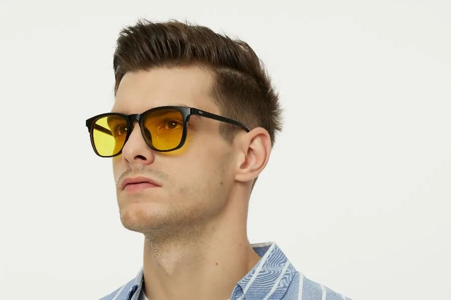Man wearing black square frames with yellow-tinted lenses