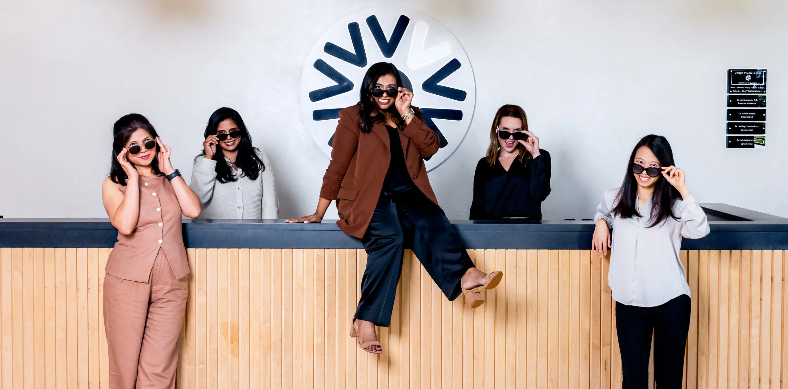 The five Village Vision Center doctors posing in sunglasses at the front desk